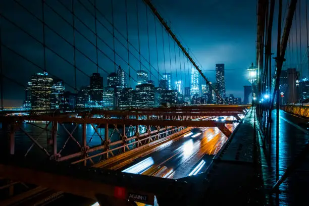 New York City Skyline seen from Brooklyn Bridge on a dark gloomy night.