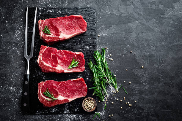 viande crue, steak de boeuf sur fond noir, vue de dessus - chop cut of meat fillet food photos et images de collection