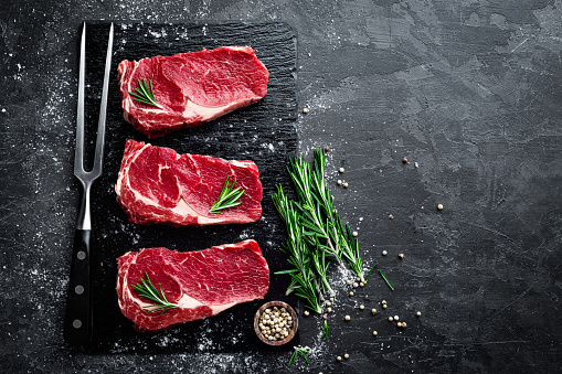 Raw meat, beef steak on black background, top view