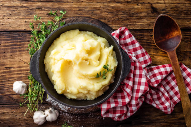 purée de pommes de terre, cuites dans une marmite en fonte sur fond rustique en bois sombre, vue de dessus - écrasé photos et images de collection