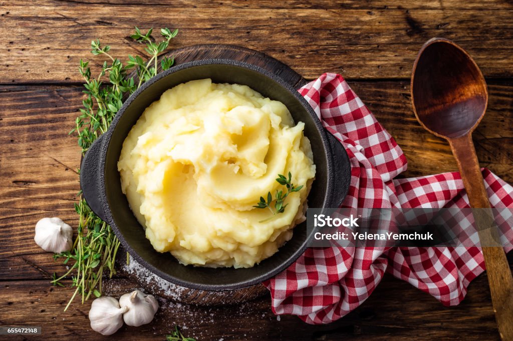 Mashed potatoes, boiled puree in cast iron pot on dark wooden rustic background, top view Mashed Potatoes Stock Photo