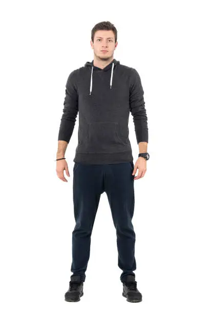 Confident willing young athletic man in sportswear looking at camera. Full body length portrait over white studio background.