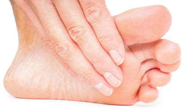 istock Person having pedicure, pulling hand under foot towards white background 655484562