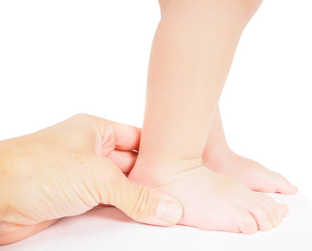 Male hand holding firmly around a foot of toddler isolated on white stock photo