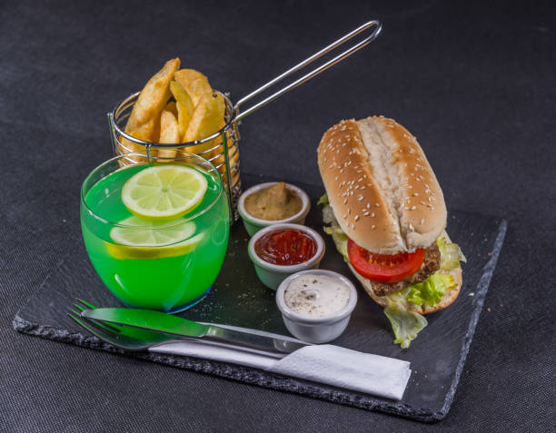 istock right view on a crusty white bread with sesame seeds, flavored with smoky rib steak bbq, barbecue sauce, lettuce, tomato, three sauces, chips in a metal basket 655484968