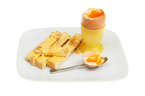 Soft boiled egg with toast soldiers on a plate isolated against white