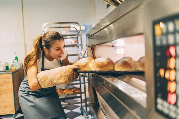 baker, tomando el pan caliente de la estufa - smelling bread bakery women fotografías e imágenes de stock