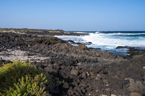 istock Black volcano stones and white sand on the coastline 655529046