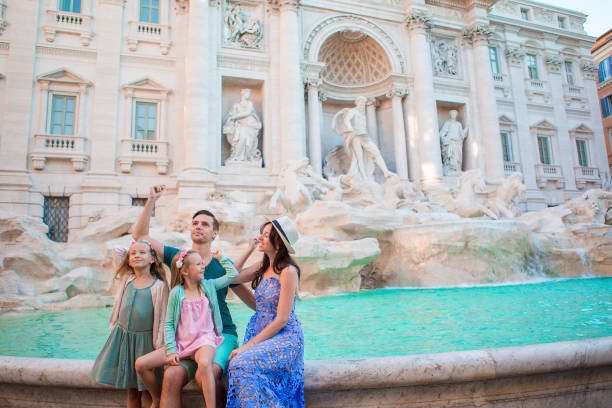 szczęśliwa rodzina trowing monety w fontannie di trevi, rzym, na szczęście. małe dziewczynki i rodzice chcą wrócić. - trevi fountain rome fountain monument zdjęcia i obrazy z banku zdjęć