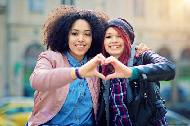 istock Two girlfriends making heart with their hands on the street 655540372