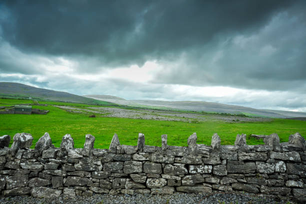 Ancient stone wall, barn, and storm clouds, on the outskirts of Kinvara, County Galway, Ireland