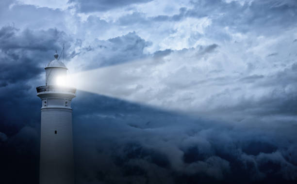 Lighthouse and bad weather in background Lighthouse shines its light at against an angry-looking sky. 

 beacon photos stock pictures, royalty-free photos & images