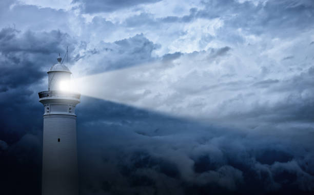 Lighthouse and bad weather in background Lighthouse shines its light at against an angry-looking sky. 

 navigational equipment stock pictures, royalty-free photos & images