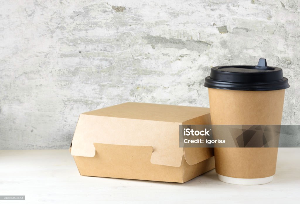 craft paper coffee cup and food box on the table craft paper coffee cup and food box on the white table near the white wall with damaged plaster Bag Stock Photo