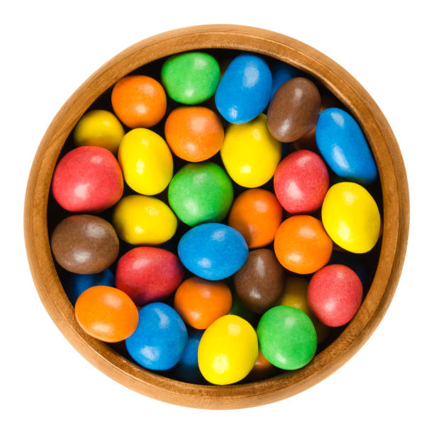 colorful chocolate peanut candies in wooden bowl over white - candy coated imagens e fotografias de stock