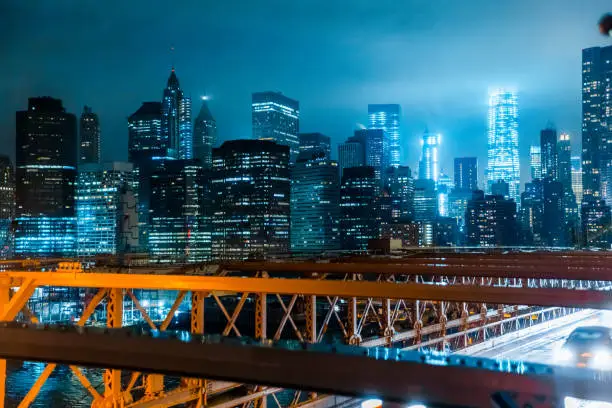 New York City Skyline seen from Brooklyn Bridge on a dark gloomy night.