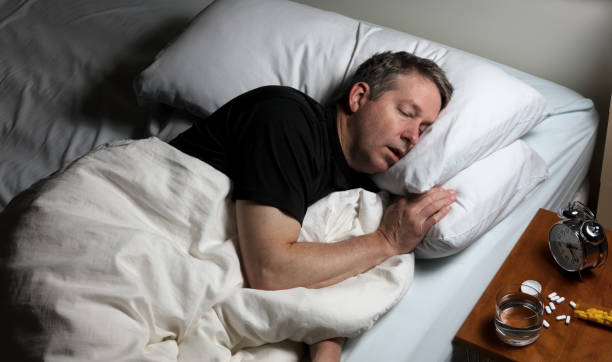 mature man attempting to fall asleep after taking medicine - narcotic medicine pill insomnia imagens e fotografias de stock