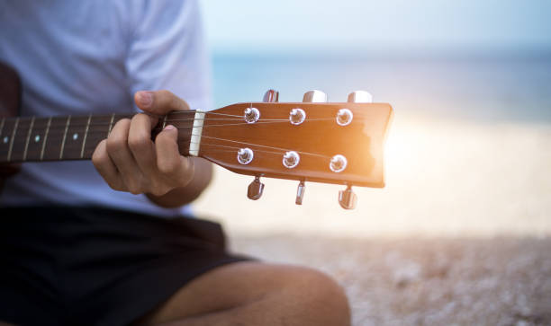 istock Close up handsome man playing classic guitar sitting on the beach in vacations 655603962