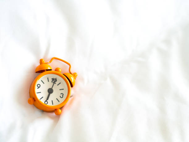 istock Alarm clock on bed in morning with sun light 655604204