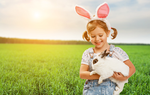 Happy easter! Pretty child girl with a rabbit in nature