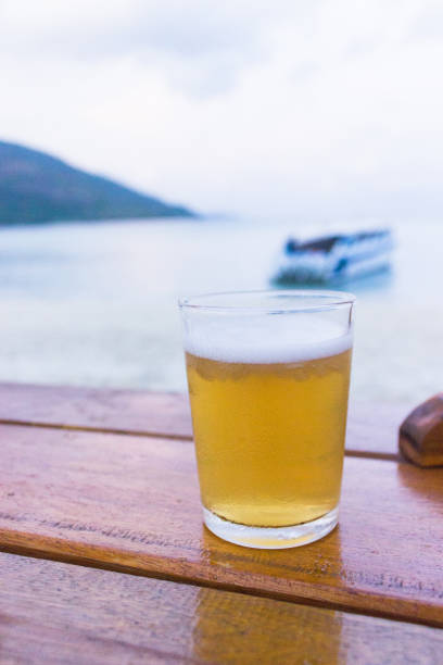 istock glass of cold beer on table near beach 655616762