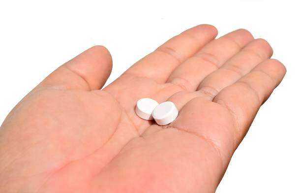 istock Two white pills in hand isolated on white background 655626960