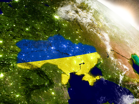 Ukraine with embedded flag on planet surface during sunrise. 3D illustration with highly detailed realistic planet surface and visible city lights. 3D model of planet created and rendered in Cheetah3D software, 9 Mar 2017. Some layers of planet surface use textures furnished by NASA, Blue Marble collection: http://visibleearth.nasa.gov/view_cat.php?categoryID=1484