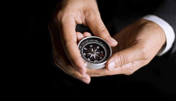 istock Businessman with a compass holding in hand on dark background 655634386