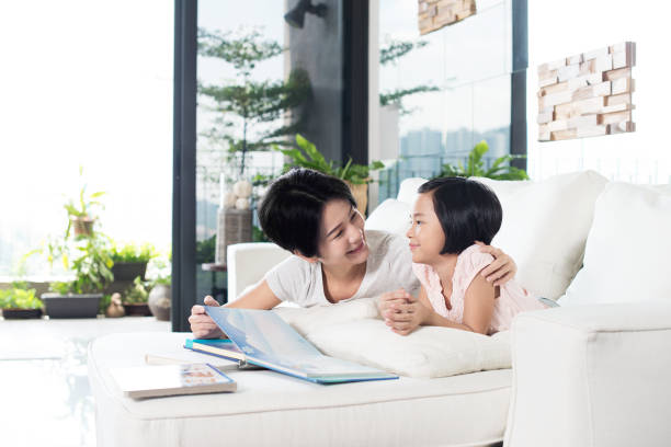 istock Asian mother and daughter reading a book at home. 655640708