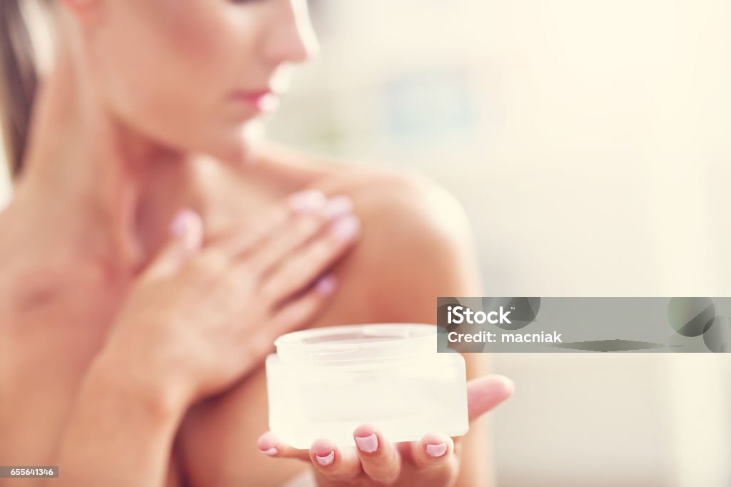 Picture of a fit woman holding lotion over her body Picture showing fit woman holding lotion over her body Cleavage - Breasts Stock Photo