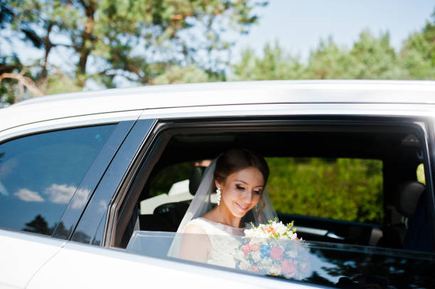 istock bride with bouquet looking from window of car 655648504