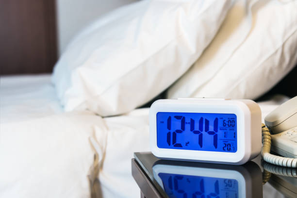 Alarm clock electronic stands on a bedside table near the bed stock photo