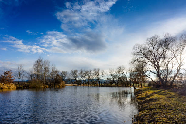 Small blue lake under the clear sky with clouds. Sunny evening mood.