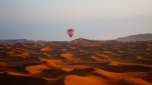 a hot air balloon flying over the Dubai Desert during a winters sunrise