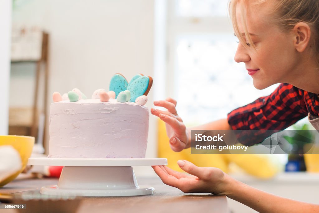 La donna decora la torta fatta in casa. Affari culinari. - Foto stock royalty-free di Donne