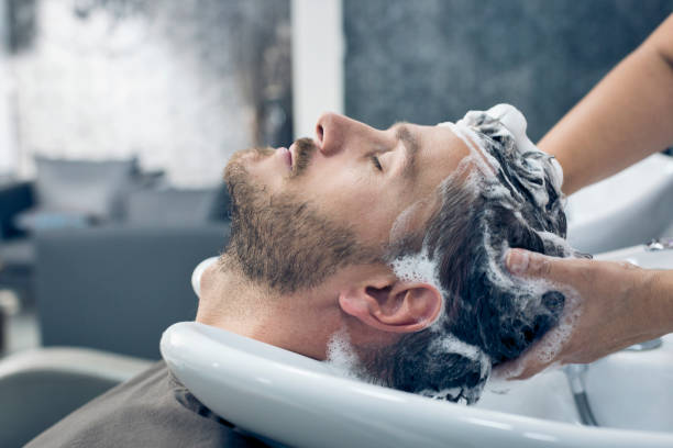 Young man getting his hair washed by a female hairdresser.