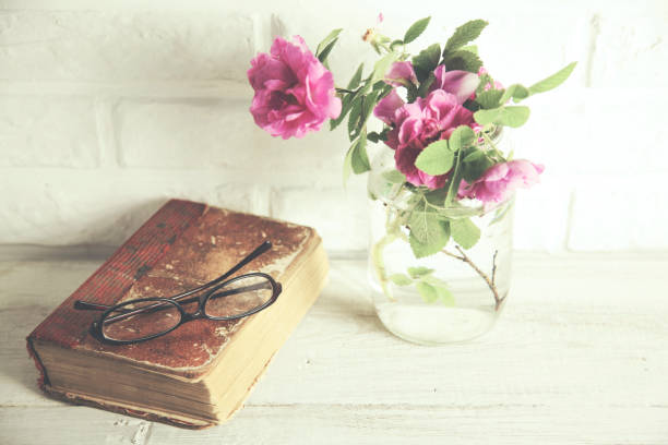 istock Pink roses in vase,books on brick wall backgrond 655691954