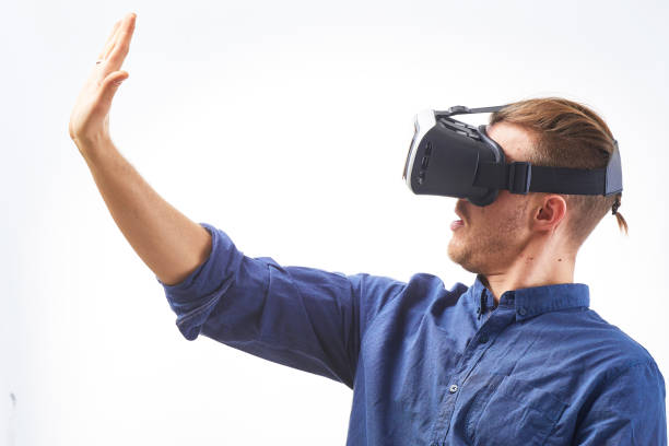 istock Young man Using VIrtual Reality Glasses for first time looking on his hand thru VR Glasses studio shot on white background 655692706