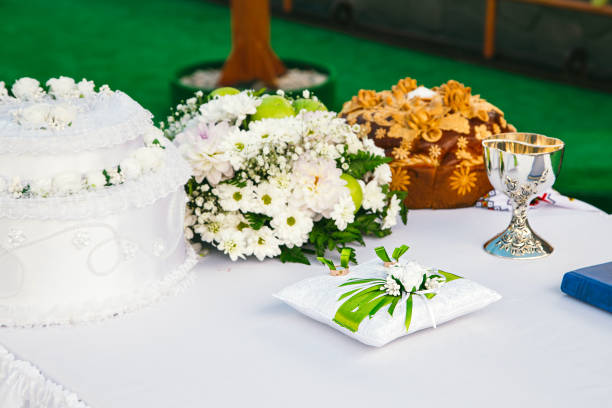 Traditional wedding loaf on the table, next to a bouquet of flowers, a pillow with rings and a wedding bowl.  Horizontal photo