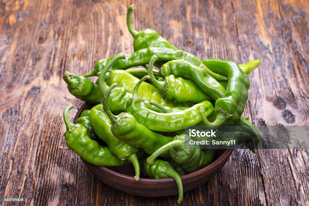 green chili peppers green chili peppers placed in a clay plate on a brown wooden table Green Chili Pepper Stock Photo