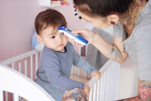 madre con termometro digitale che controlla la temperatura - child fever illness thermometer foto e immagini stock