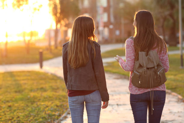 друзья гуляют вместе на закате - walking girl стоковые фото и изображения