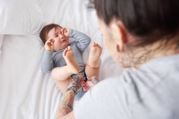 mother changing crying babys nappie - offspring child lying on back parent imagens e fotografias de stock