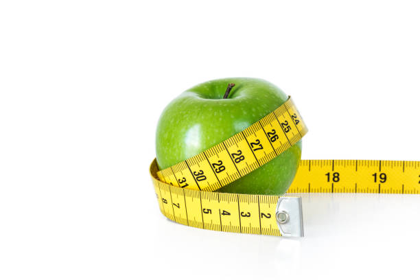istock Green apple with tape measure on white background 655727928