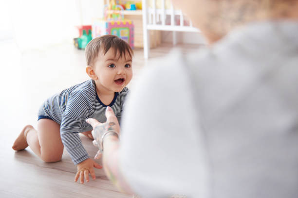 istock Mother watching baby son crawl towards her 655728850