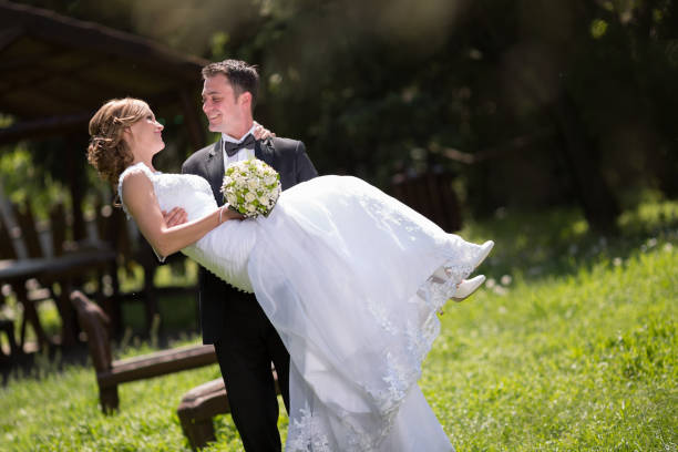 istock Groom carrying bride outdoors and smiling 655757588