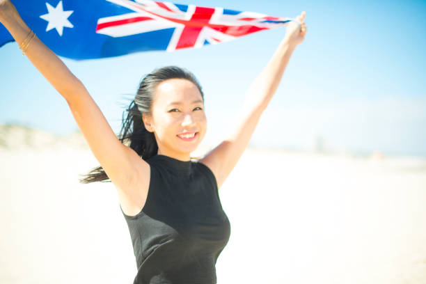 mixed race beautiful woman celebration citizenship on australian beach - australia australia day celebration flag imagens e fotografias de stock