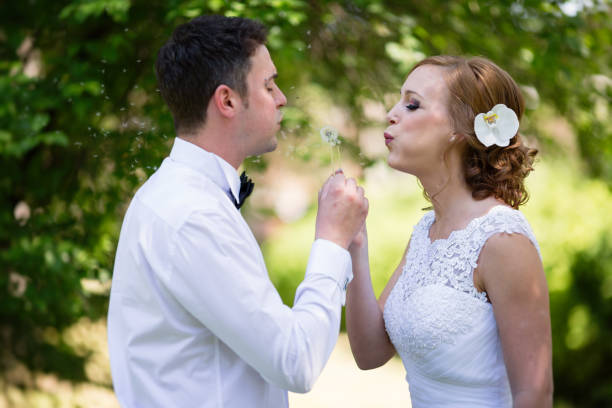 istock Beautiful couple blowing dandelions after getting married 655758378