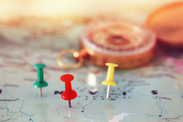 istock pins attached to map, showing location or travel destination and old compass. 655771746