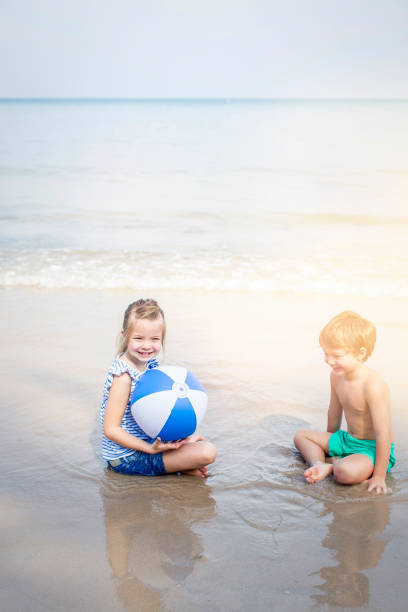 istock girl and boy playing water ball on the beach 655773302